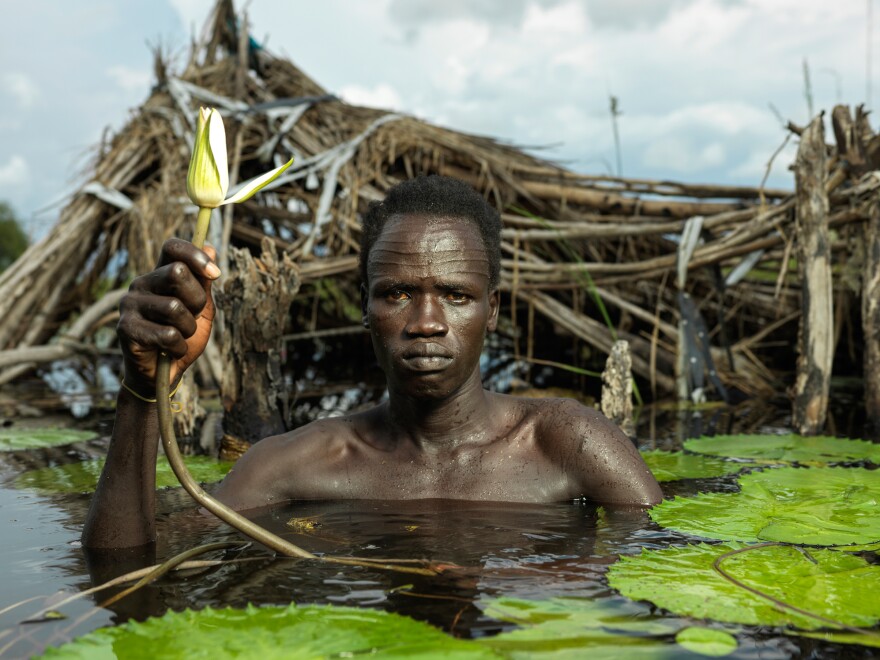 Majiel Duoth, 35, stands in front of his destroyed home in Old Fangak. He now lives on a small grass island with eight others who have been displaced. (September 2021)