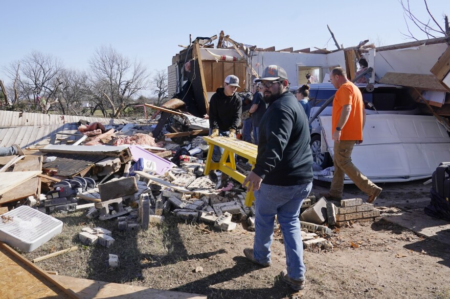 Adam Lee (left) and Jr. Ibarra carry a table from a friend's home on Tuesday after it was destroyed by a tornado in Wayne, Okla.