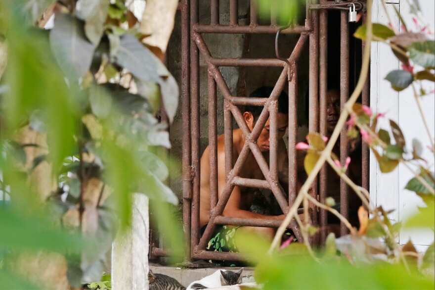 Thai and Burmese fishing boat workers sit behind bars inside a cell at the compound of a fishing company in Benjina, Indonesia. The imprisoned men were considered slaves who might run away. They said they lived on a few bites of rice and curry a day in a space barely big enough to lie down, stuck until the next trawler forces them back to sea.