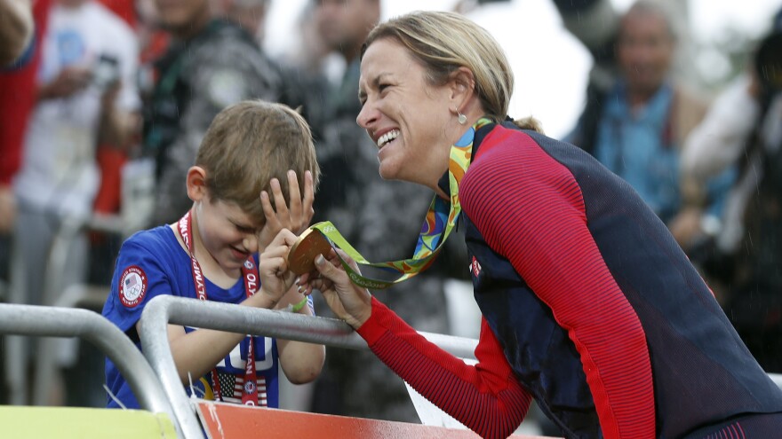 Cyclist Kristin Armstrong of the United States shows her gold medal to her 5-year-old son, Lucas, after she won the women's individual time trial on Wednesday. Armstrong, who turns 43 on Thursday, became the first cyclist to win the same event in three Olympics.