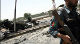 An Afghan National Policeman walks past the remains of a U.S. armored vehicle after it was struck by a suicide car bomber in Jalalabad, Afghanistan.
