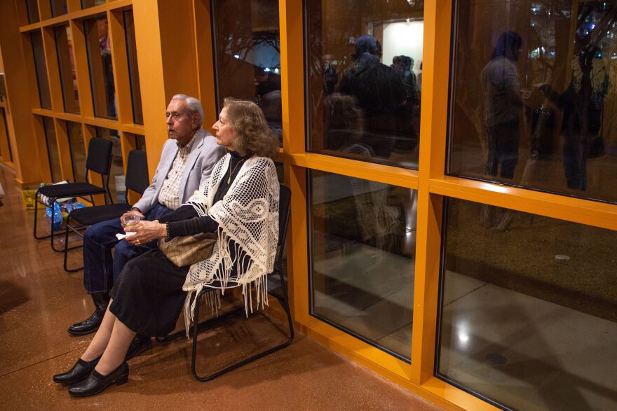 A man and a woman rest in chairs in a lobby. 