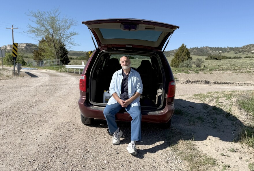 Roger McDonald sits in the back of his preferred rural mail delivery vehicle, a Dodge Caravan, on a gravel road along his 150-mile route outside Scottsbluff in northwestern Nebraska on May 11, 2025. The 61-year-old letter carrier worries about what would happen to his customers, his coworkers and himself if the Postal Service further curtailed service or was privatized.