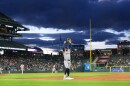 Several baseball players stand on the field of a large stadium
