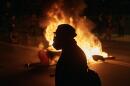 A man wearing protective gear walks in front of a burning barricade outside the Delaney Hall detention center during a protest against the transfer of detainees and federal immigration policies on Saturday, May 30, 2026, in Newark, N.J. (Andres Kudacki/AP)