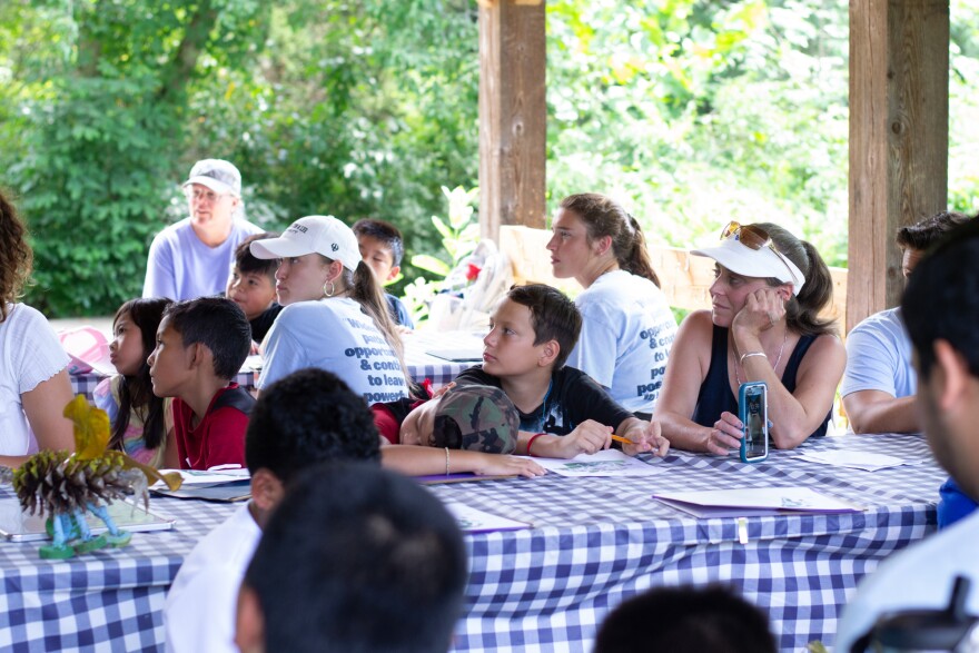 Jayne Reino, at right, sits with the students under a pavilion at the nature center.