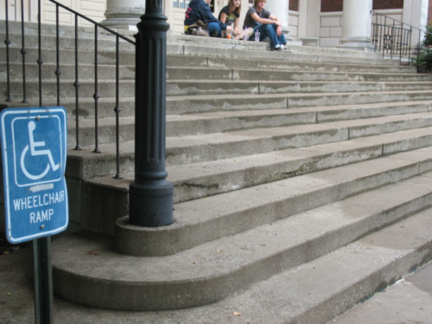A handicap sign near a large flight of stairs on Murray State's campus. The ramp is around the corner.