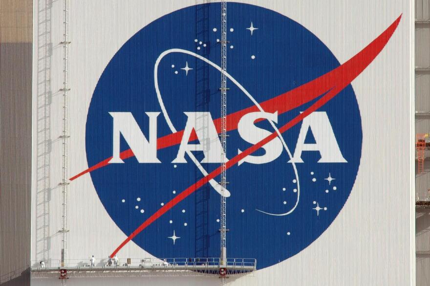 The NASA logo shines in the morning sun on the side of the Vehicle Assembly Building after completion of its repainting. The logo, which is known as the "meatball," measures 110 feet by 132 feet, or about 12,300 square feet. The American flag was also painted on the side of the VAB. The flag spans an area 209 feet by 110 feet, or about 23, 437 square feet. Each stripe is 9 feet wide, and each star is 6 feet in diameter. The flag and logo were last painted in 1998, honoring NASA's 40th anniversary.