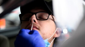 Nathaniel Rivard 20, of Naugatuck leans back as COVID collection specialist Jon Schwartz administers a swab test during Griffin Health's COVID-19 drive-thru testing site at Tunxis community college on November 12, 2020 in Farmington, Connecticut.