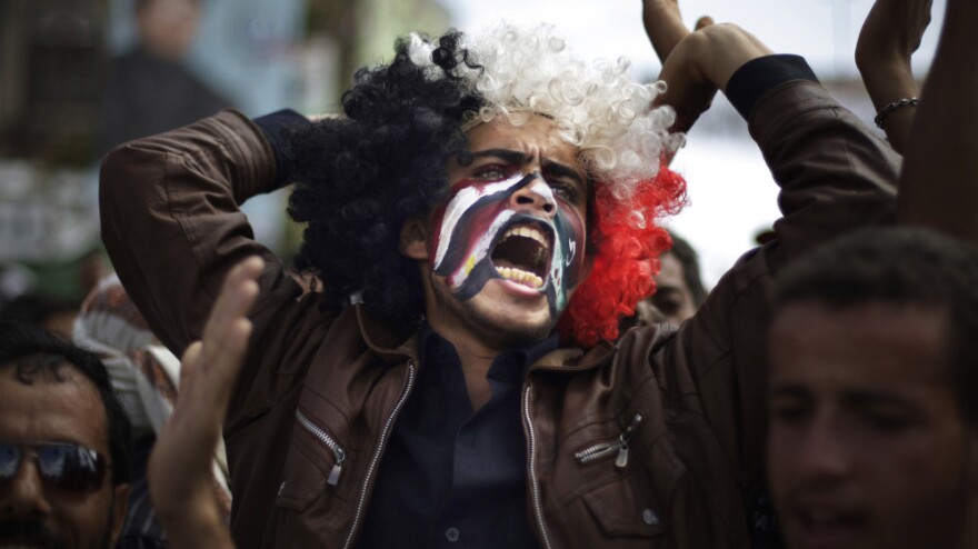 A protester with Yemeni, Egyptian, Libyan and Syrian flags painted on his face chants slogans during a demonstration Wednesday in Sanaa, Yemen, against a deal that grants immunity for President Ali Abdullah Saleh.