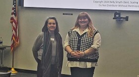 Two women pose for a photo in a conference room