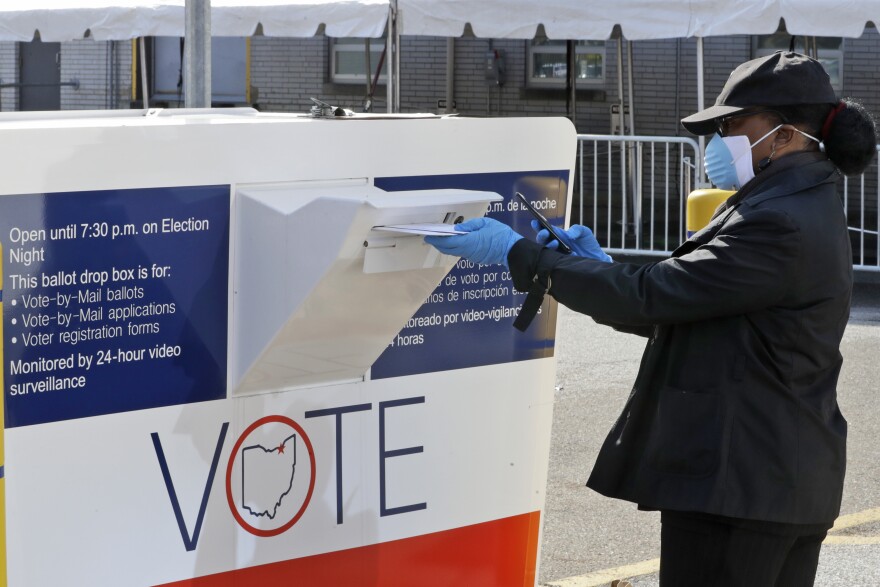 In this April 28, 2020 file photo, Marcia McCoy drops her ballot into a box outside the Cuyahoga County Board of Elections in Cleveland, Ohio.