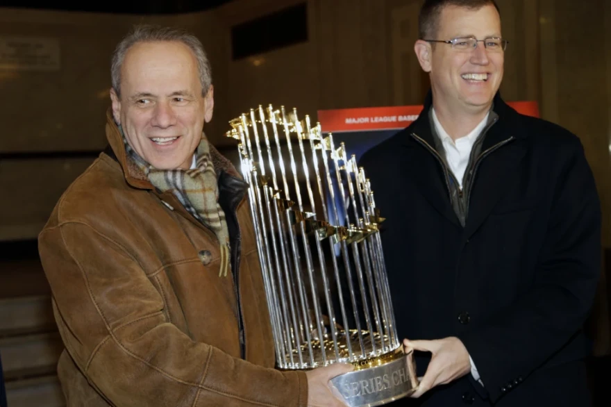 FILE - Boston Red Sox CEO Larry Lucchino, left, and Chief Operating Officer Sam Kennedy hold the 2013 World Series baseball trophy on the red carpet at the Wang Theatre before a screening of a DVD about the series in Boston, Nov. 23, 2013.