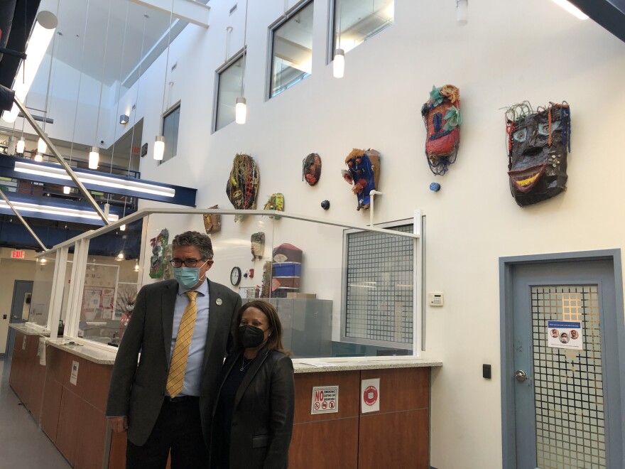 Health Care for the Homeless CEO Kevin Lindamood (left) and HUD Deputy Secretary Adrianne Todman (right) pose in front of masks made by the clinic's art group. Credit: Sarah Y. Kim/WYPR