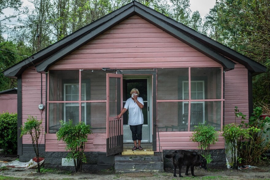 Activist Elsie Herring, stands on the porch of her family home, holding a handkerchief over her mouth to filter out manure being sprayed on the field next door