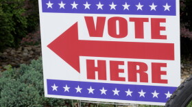 A red white and blue sign with an arrow that says "vote here"