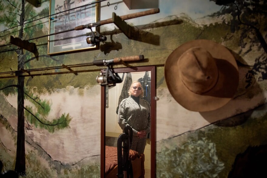 Kelly Frost is reflected in a mirror next to Jeffrey Butler’s fishing poles in Douglas City on Dec. 4, 2025.