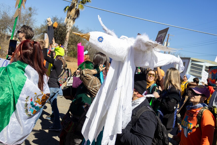 Sheila Vasquez holds a large bird sculpture she calls “Protectors,” which she says represents hope for families inside the ICE detention center.