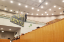 At a CMS school board meeting, an attendee unfurls a banner to protest ICE at schools.