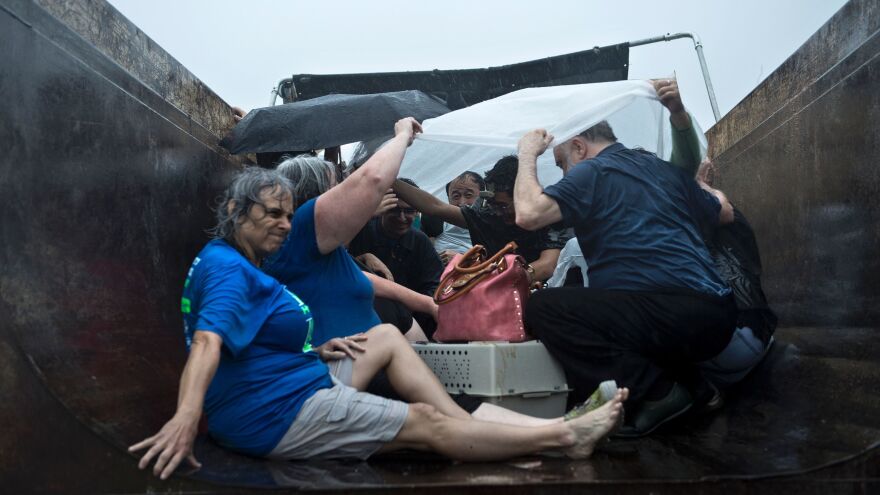 People wait to be taken out in a city dump truck on an overpass in Houston on Sunday. The most powerful storm to hit the U.S. in years, Hurricane Harvey left a trail of devastation across Texas over the weekend, destroying homes, severing power supplies and forcing tens of thousands of residents to flee.