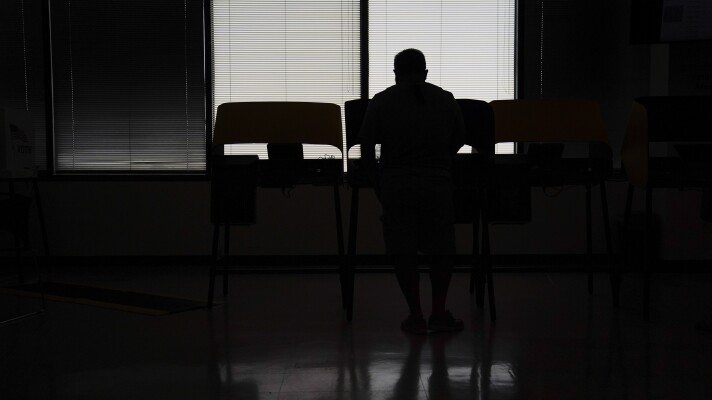 A voter is silhouetted as he casts an early ballot for the California gubernatorial recall election at a vote center, Tuesday, Sept. 7, 2021, in Norwalk, Calif. (AP Photo/Jae C. Hong)
