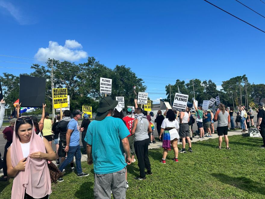 People stand on sidewalk waving signs supporting the rights of immigrants