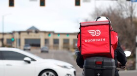 FILE - A food delivery motorcycle rider waits for the traffic light to change March 30, 2020, in Lone Tree, Colo. (AP Photo/David Zalubowski, File)
