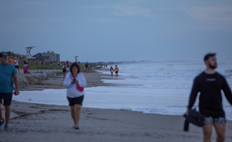 Visitors stroll along the beach to watch larger than normal waves caused by Hurricane Erin near Johnnie Mercers Fishing Pier in Wrightsville Beach, North Carolina on August 20 2025.