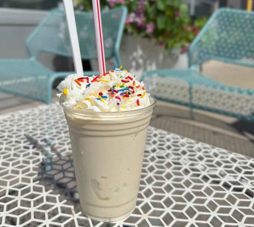 A milkshake with whipped cream and sprinkles on a geometric patterned outdoor table at Fairway Creamery.