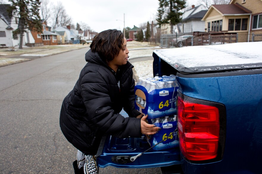 McDonald unloads cases of bottled water to take to her godbrother Brent Diggs, who is handicapped and often unable to pick up water himself, at his home in Flint.