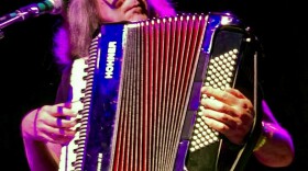 A man sitting playing an accordion. 