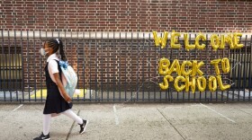 A girl passes a "Welcome Back to School" sign as she arrives for the first day of class an elementary school in New York on Sept. 13, 2021. (Mark Lennihan/AP/File)