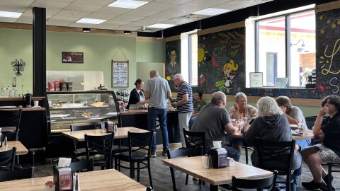 Patrons sit at tables and order food at a cafe and coffee shop.