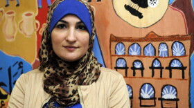 Linda Sarsour, director of the Arab American Association of New York, poses for photos in front of a canvas painted by the association's youth group at its headquarters in the Brooklyn borough of New York in December 2011. (Henny Ray Abrams/AP)