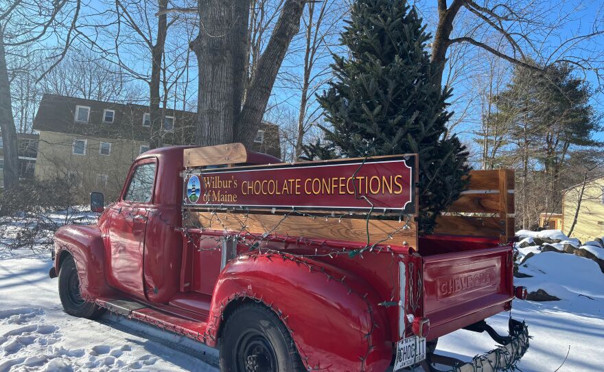 A red truck with a Christmas tree in the back at Wilbur's of Maine Chocolate Confections in Freeport, Maine.