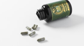 An open bottle of Kratom with capsules on a table