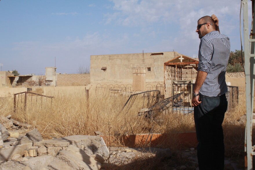 Taher Bahoo stands in a damaged graveyard in his home village of Karamlesh.
