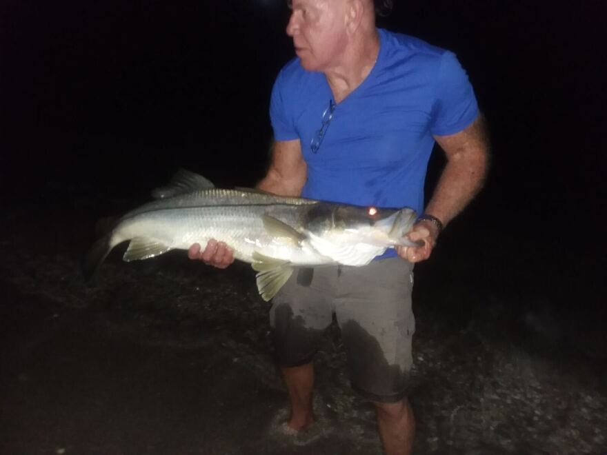 Man in blue shirt holds fish 