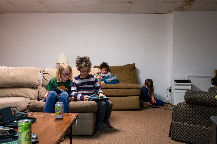 Henry Partain and Henry Pham (front left to right) play on iPads while Hayle Pham and Jack Partain play Nintendo Switch after skiing in Seven Springs, Pa., on Feb.16, 2020.