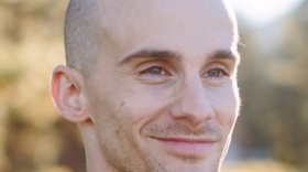 Headshot of Noah Glick. He is looking away from the camera and smiling.