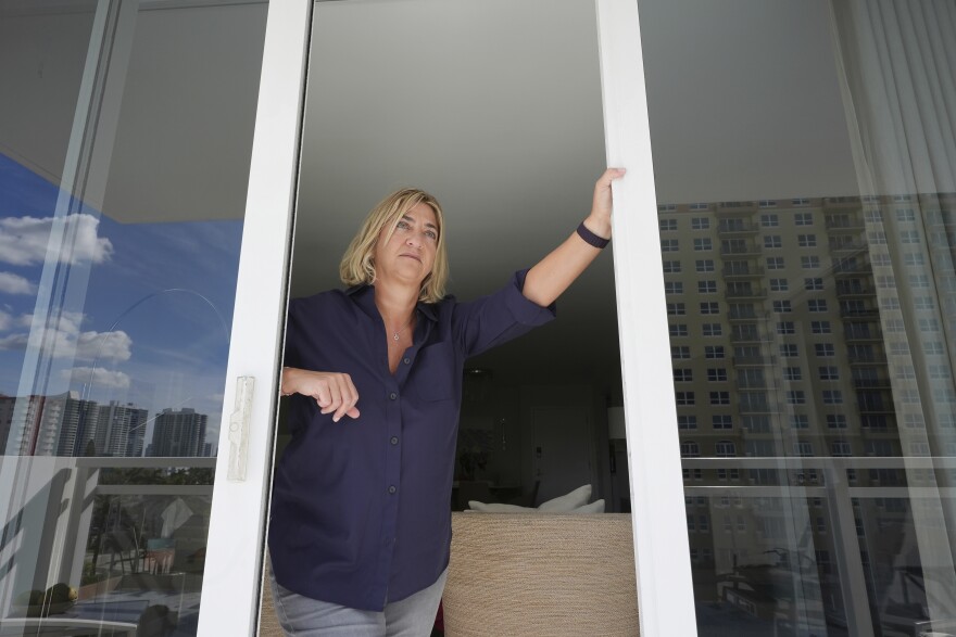Kelli Roiter, a condo owner in one of the few residential buildings designed in 1971 by architect Morris Lapidus, looks out her balcony at other waterfront high-rise buildings, Thursday, Dec. 5, 2024, in Hallandale Beach, Fla. Roiter supports new rules that require condo associations to maintain reserves and make necessary structural repairs.