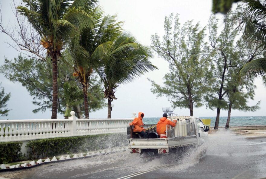 Landscapers ride in a truck along a stretch of road that's partially flooded from rain triggered by the arrival of Hurricane Matthew, in the eastern district of Nassau, Bahamas, Wednesday, Oct. 5, 2016. Forecasters said the storm was on track to roll directly over the capital city before nearing the Florida coast. (AP Photo/Craig Lenihan)