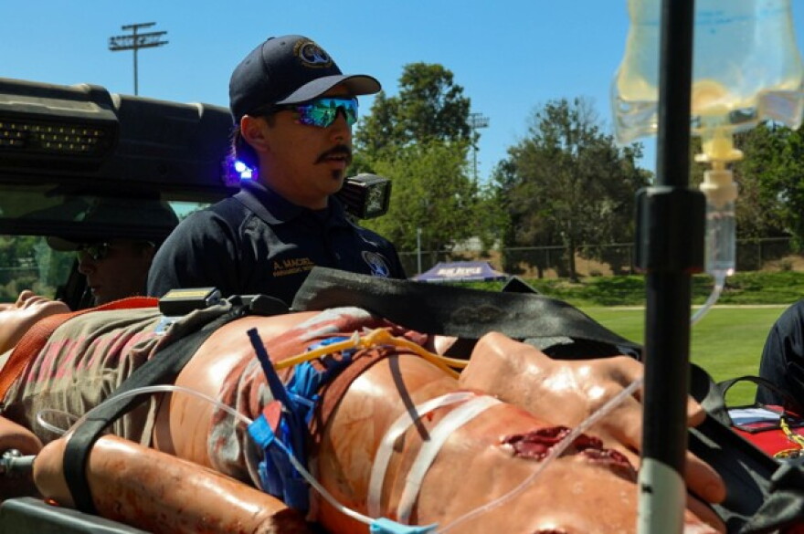 Alex Maciel sits in the back of the vehicle with a patient dummy while they are transported to the ambulance.