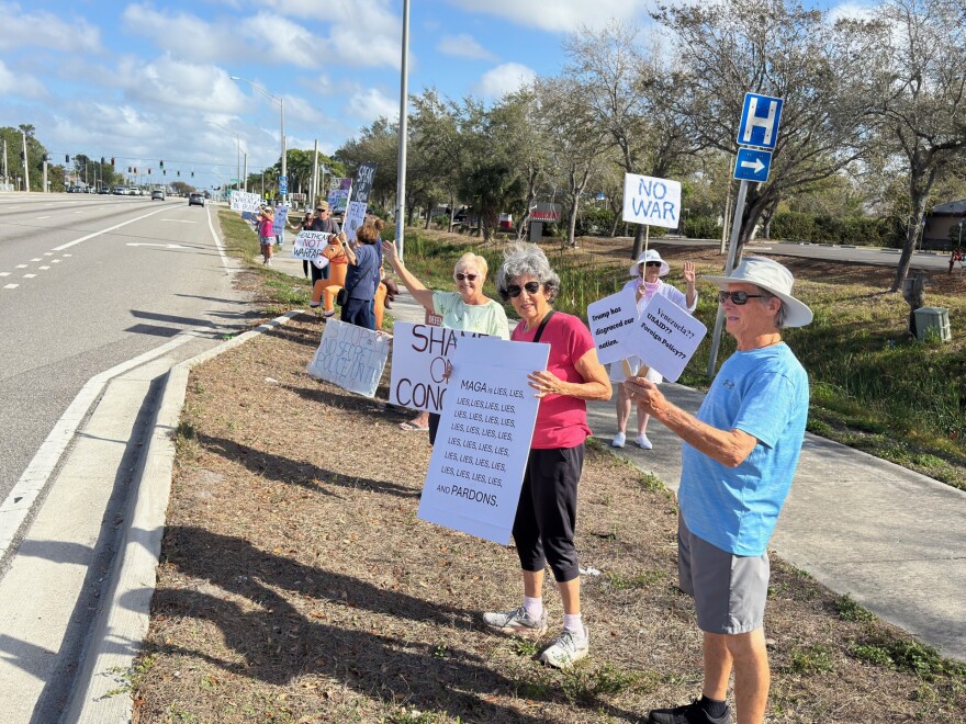 About a dozen people stood along US 41 near Daniels Parkway Saturday to protest US war activity in Iran.
