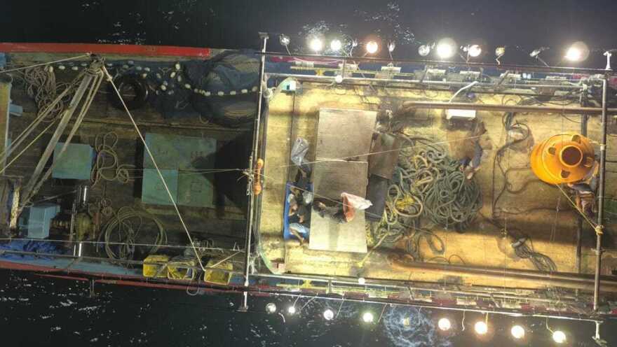 View of an Asian fishing vessel, with men asleep on deck.