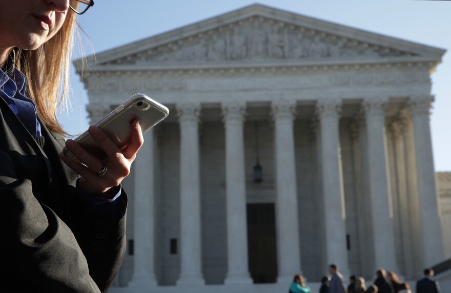 A woman checks her cellphone as she waits in line to enter the Supreme Court on Wednesday to hear arguments in Carpenter v. United States about the government's access to cellphone data.