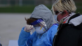 Employees doing COVID-19 testing wear considerable amounts of personal protective equipment.
