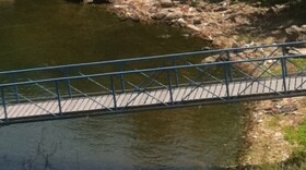 Blue-Green Algae is visible in the water and washed up on the shore at a Grand Lake dock near the dam.