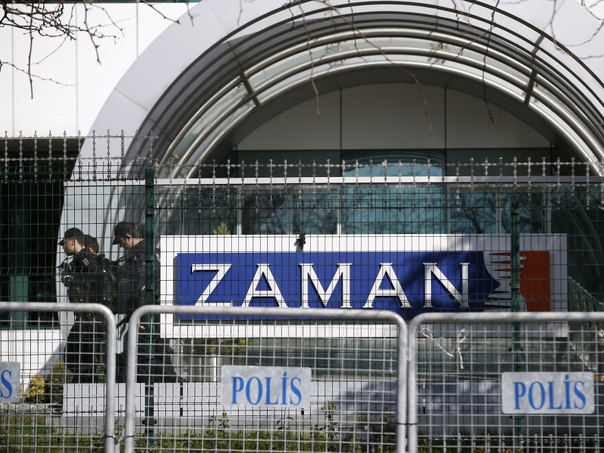 Riot police officers walk past the headquarters of <em>Zaman</em> newspaper, surrounded by police barriers in Istanbul, on March 6. Police used tear gas and water cannons to disperse hundreds of protesters who gathered in support of the paper outside its headquarters.