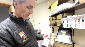 A man holds up a container of blood in a medical room.